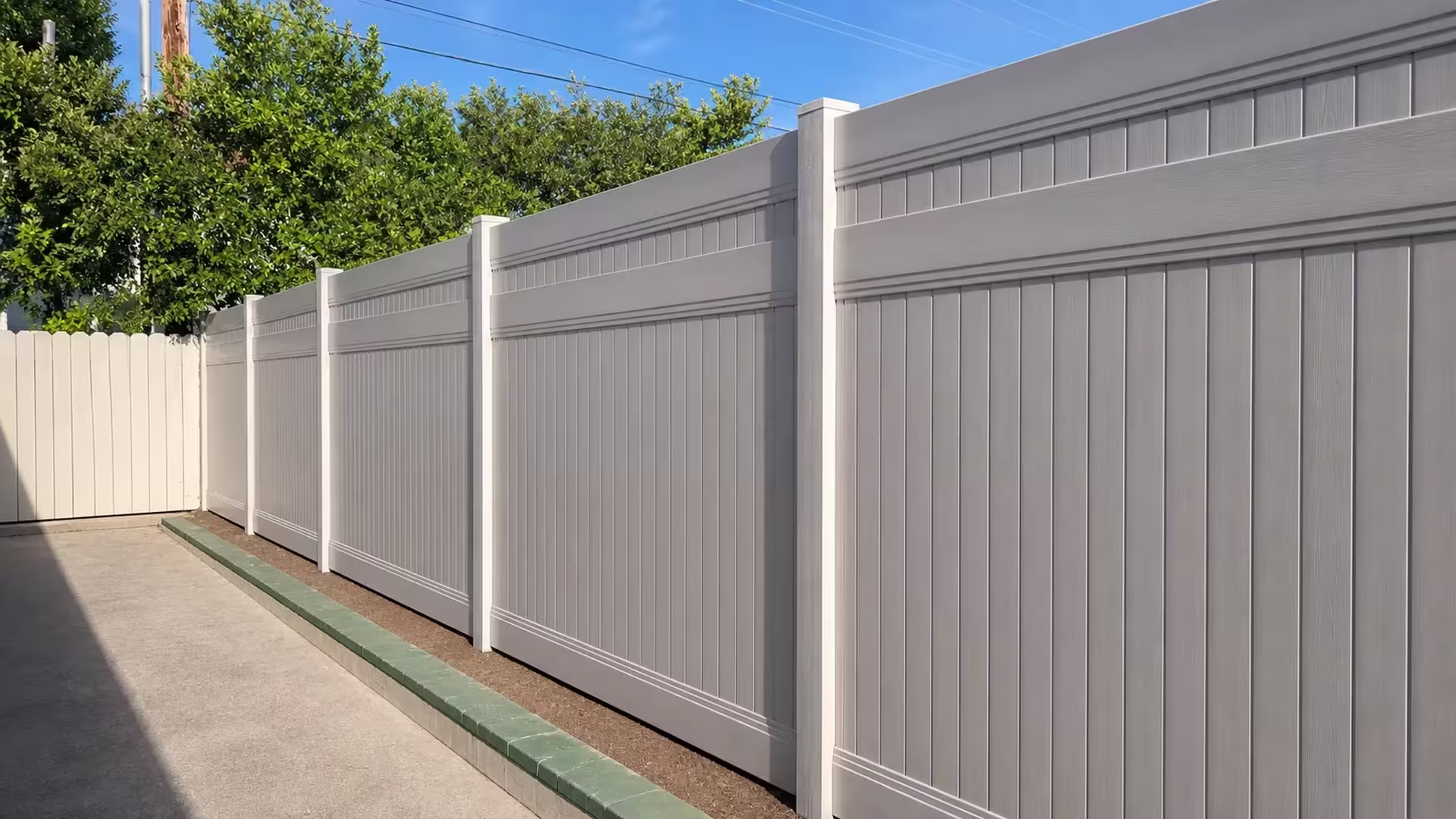 Tan vinyl privacy fence with a lattice top running past an old pale fence section in Glendale