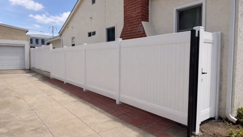 Gray-trimmed windows and a red-brick strip flank this vinyl privacy fence, finished in White, in Culver City