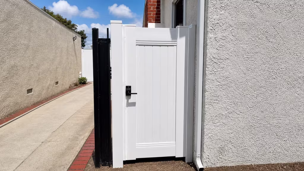 Beside a stucco house, a White vinyl gate leaf matches the privacy fence in Culver City