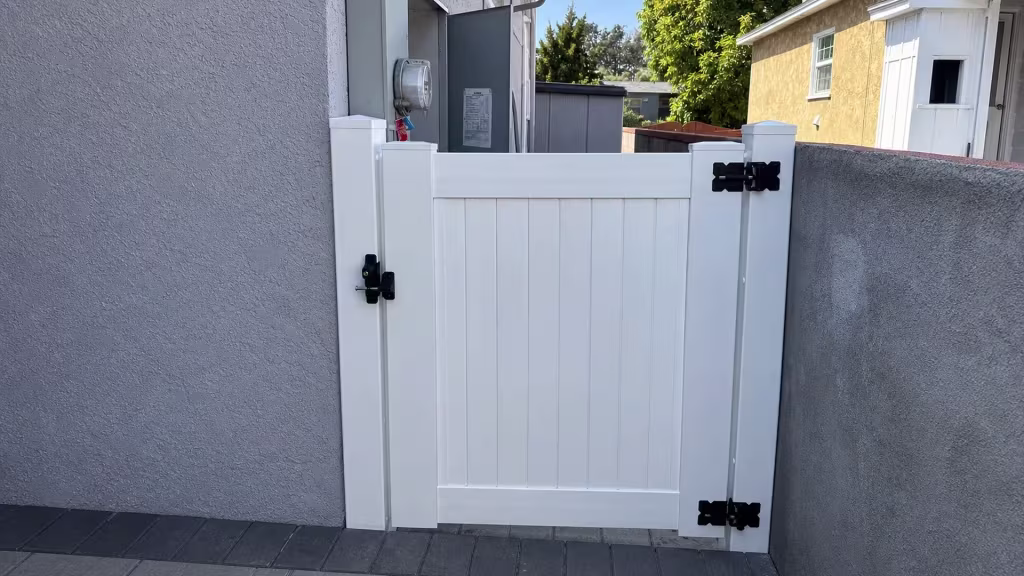 Mounting posts and hinge hardware frame this Arleta privacy gate, its White vinyl surface carrying dark acrylic openings