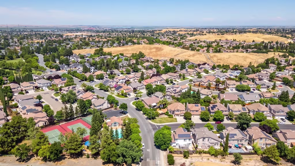 Aerial view over Antioch, where residential neighborhoods meet open golden hills and distant mountains