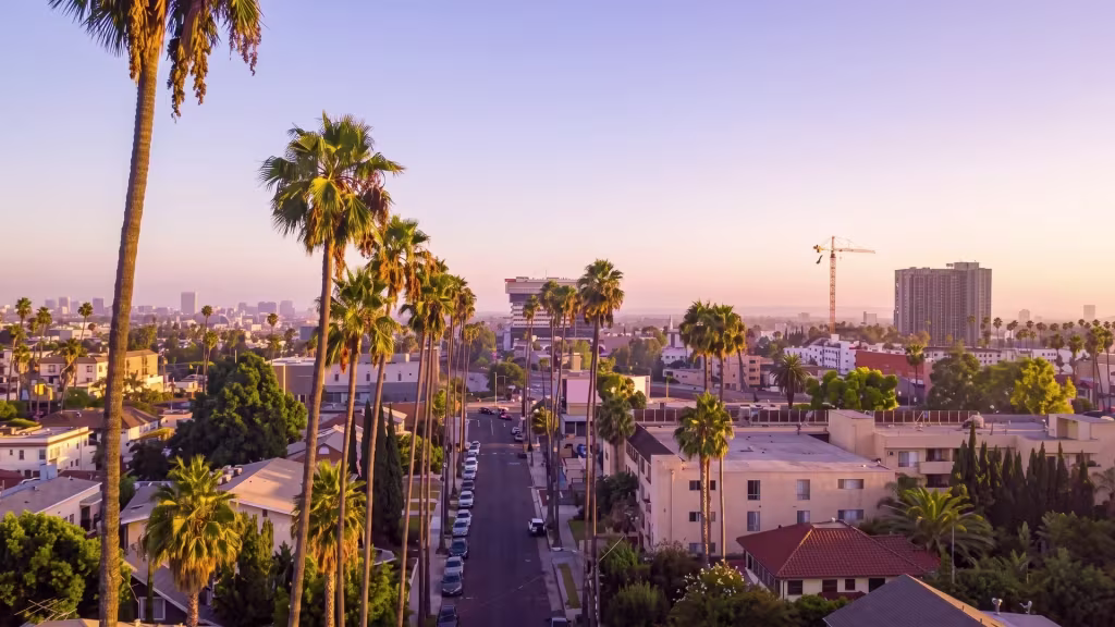 Bell Gardens catches sunset light across its palm-lined urban neighborhood in this elevated oblique view