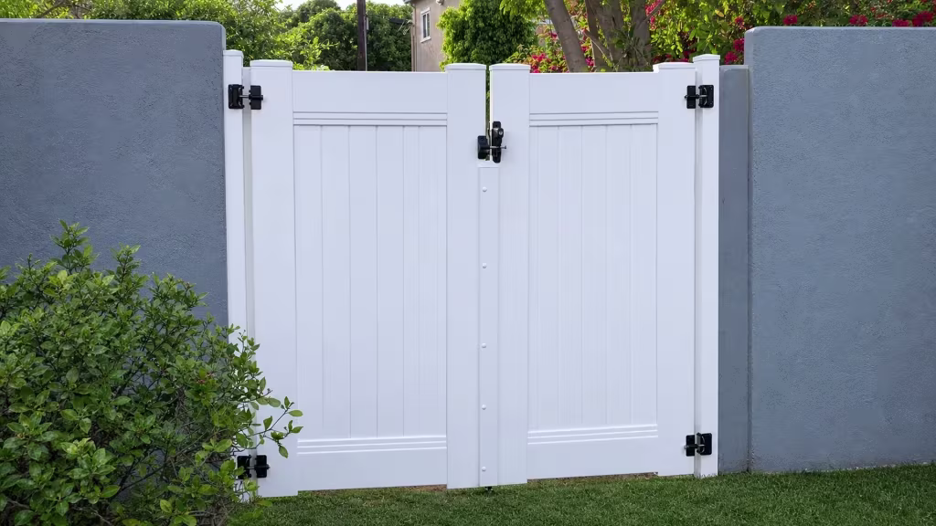 White vinyl double leaf gate matching the privacy fence beside a stucco building in North Hollywood