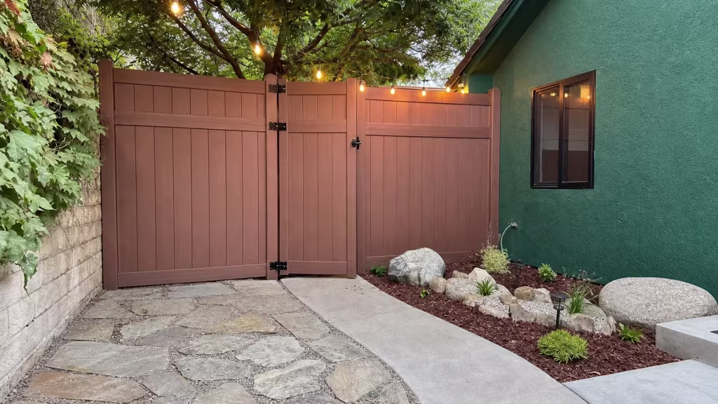 A dark-framed window sits by this vinyl privacy fence, where a Dark Walnut gate closes the Thousand Oaks courtyard