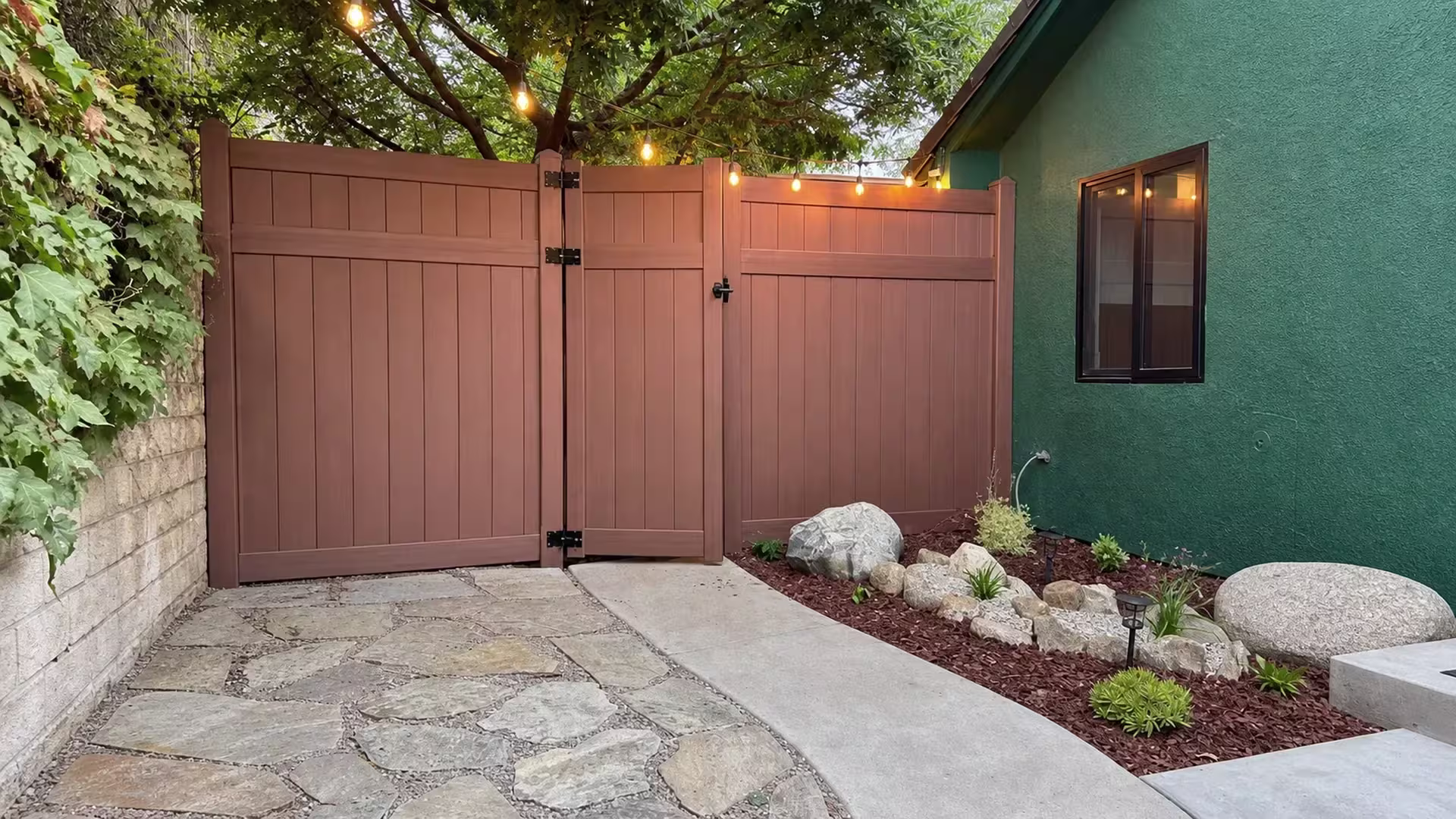 A dark-framed window sits by this vinyl privacy fence, where a Dark Walnut gate closes the Thousand Oaks courtyard