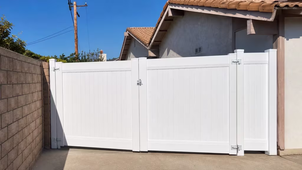 Terracotta tiles and a wooden utility pole rise behind this vinyl fence gate, finished in White, at a Simi Valley driveway