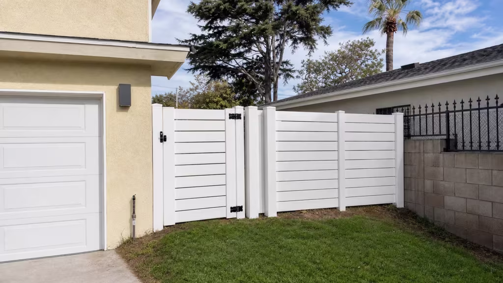 Mature evergreen and palm trees frame the White horizontal picket vinyl fence along this Torrance side yard