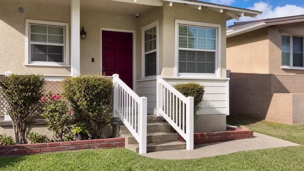 A brown shingle roof with exposed rafter tails caps this White vinyl picket fence in Burbank