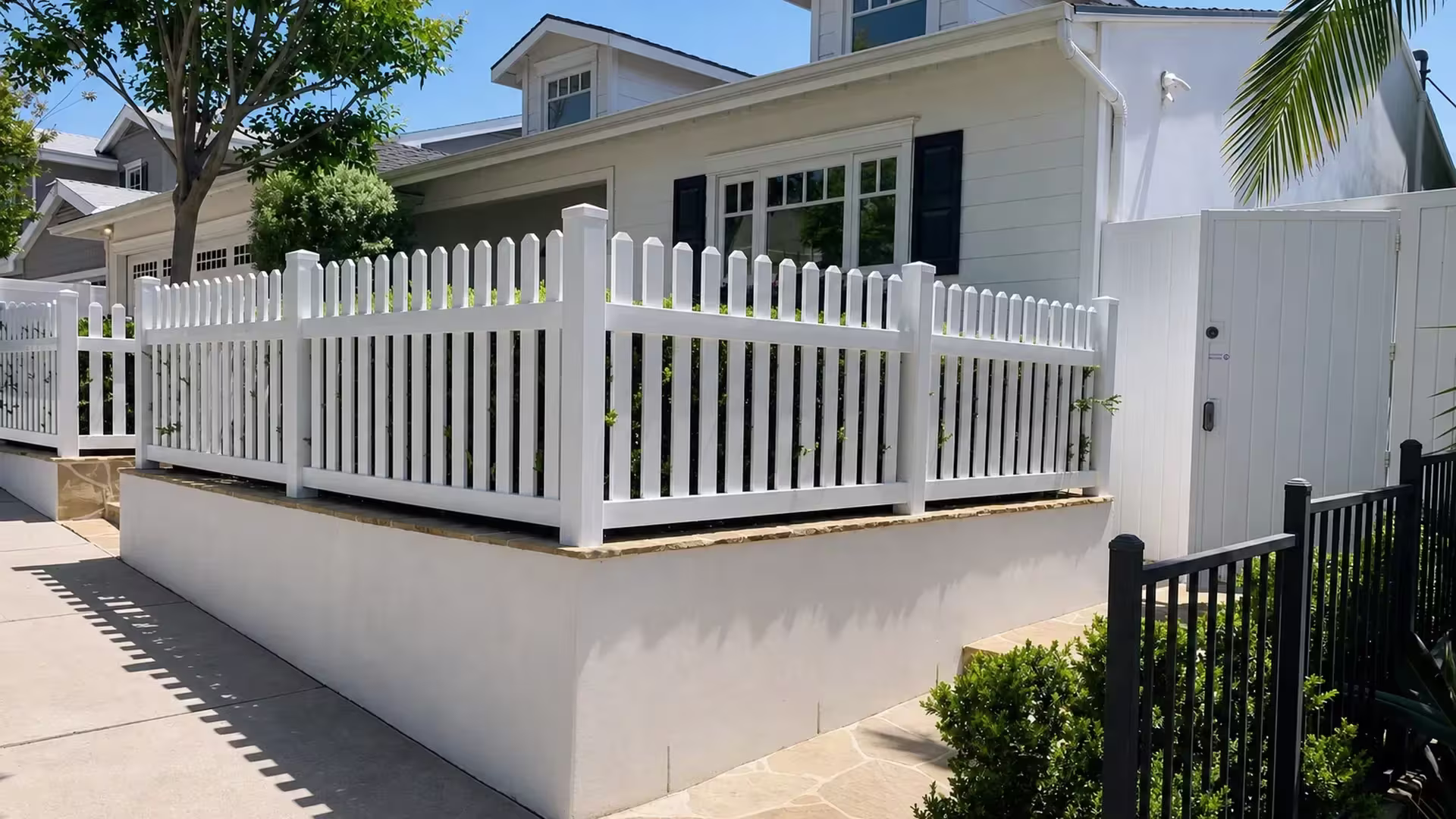 Pyramidal post caps top a White vertical vinyl picket fence set atop a Pacific Palisades retaining wall