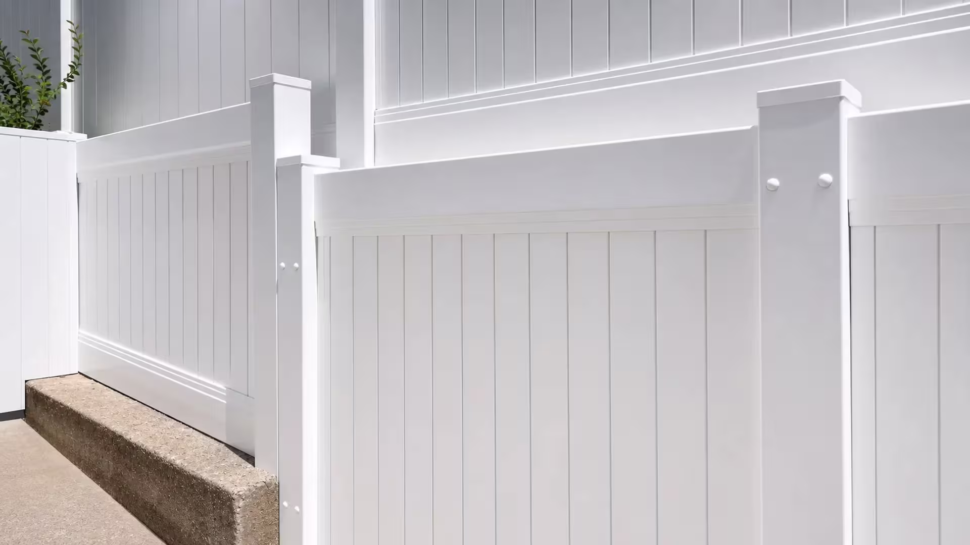 A gray metal siding building borders this White vertical vinyl picket fence along a narrow Pacific Palisades side yard