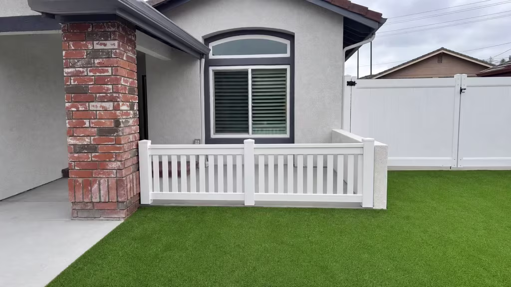 White vinyl picket fence lines the Yorba Linda entry between a brick porch column and a stucco return wall