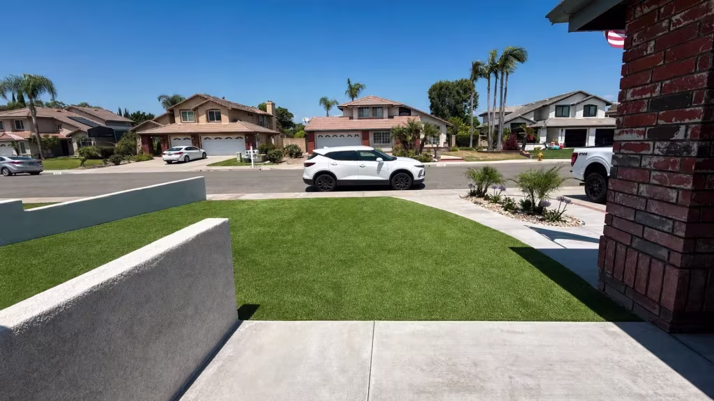 Before installation, an open front lawn faces the sidewalk and street between low stucco walls.
