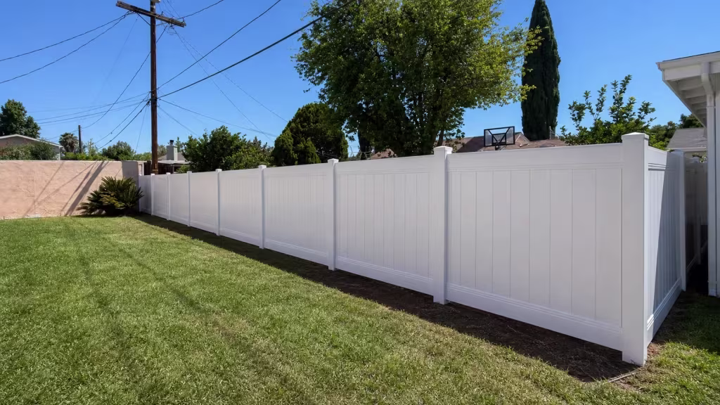 A cycad and a basketball backboard stand beyond this vinyl fence, finished in White, bordering an Encino lawn
