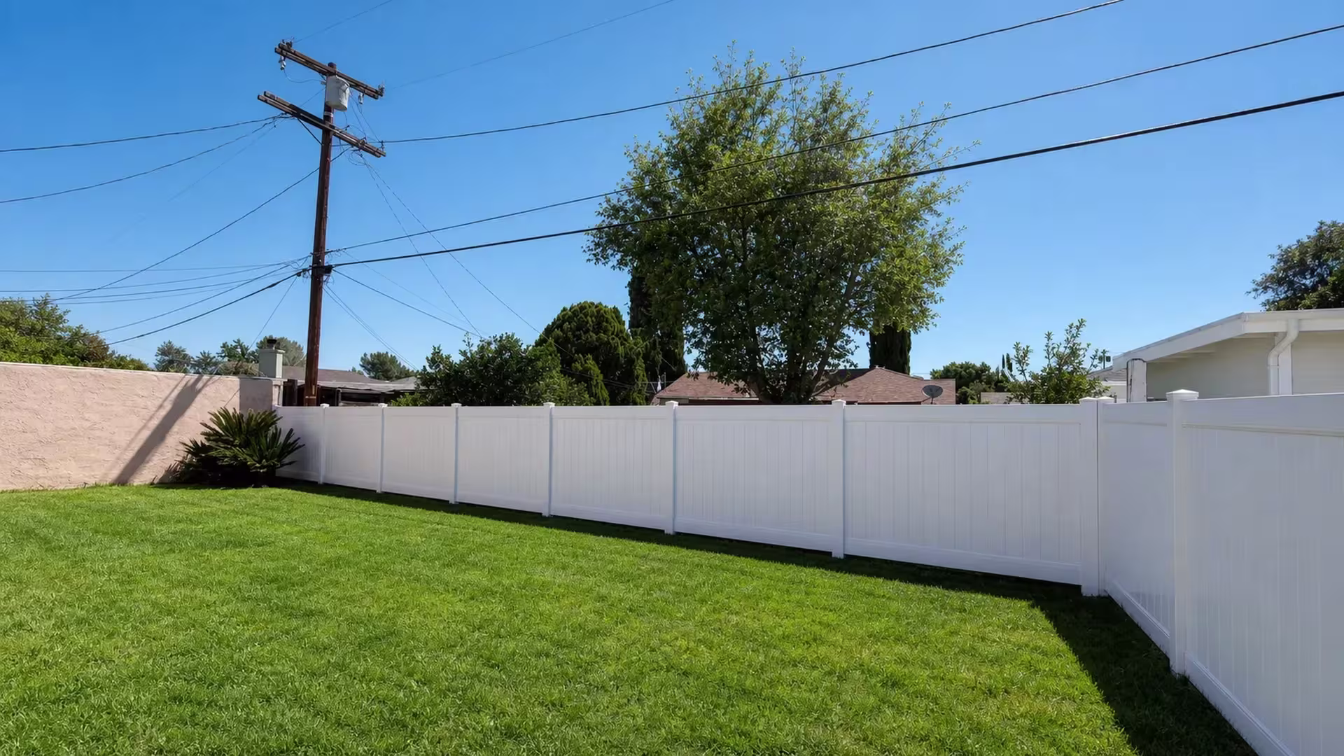 Smooth-finish White vinyl privacy fence panels run along a brick wall boundary in Encino