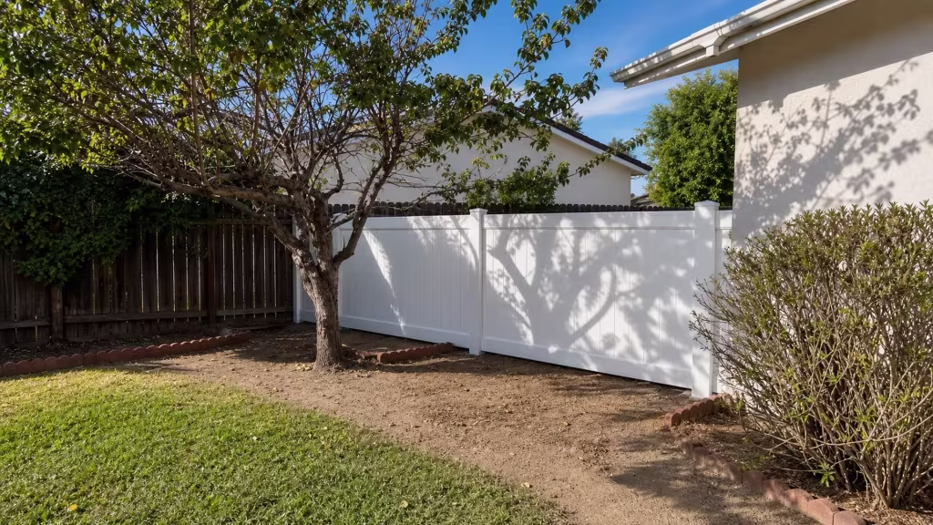 In Arcadia, an older dark wood boundary fence stands behind this White vinyl privacy fence