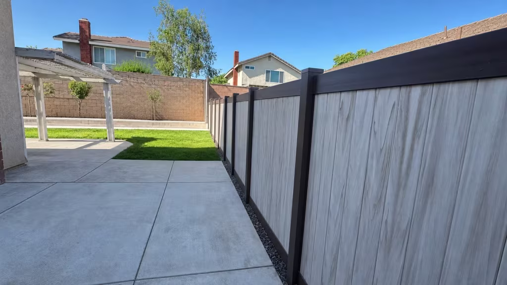 Two-tone Dark Walnut and aspen vinyl privacy fence set diagonally beside a pale pergola in Chino