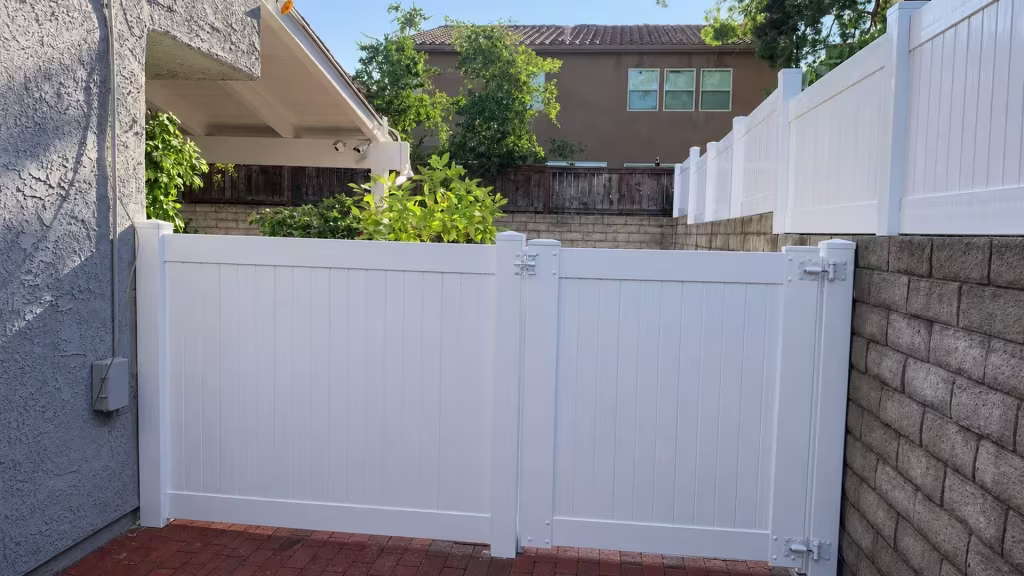 White vinyl privacy wall topper fronting a brick-paved side yard beside an older dark wood fence
