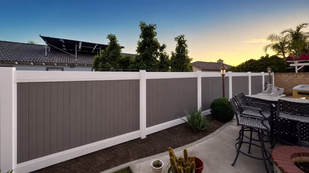 This White vinyl fence carries a gray two-tone finish past potted cacti toward a dining patio in Rancho Cucamonga
