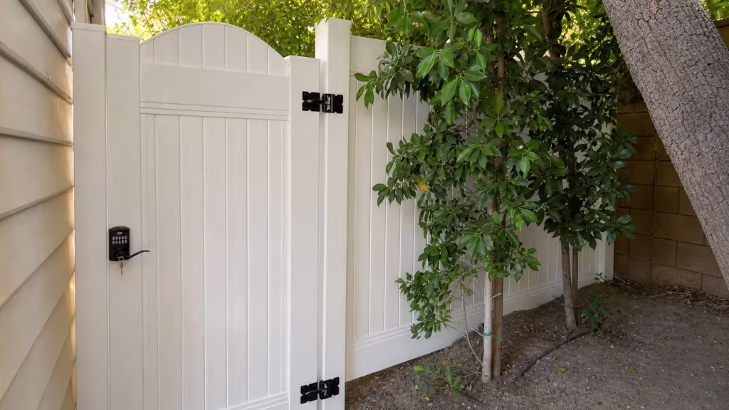 An irrigation line runs beside this White vinyl fence and gate set along a shaded San Marino side yard