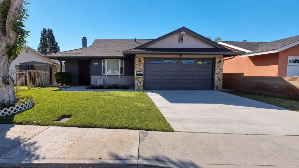 Before installation, the front yard and driveway sit between a low block wall and an older metal fence.