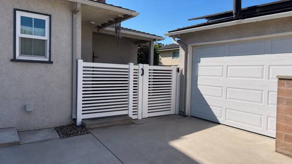 Solar panels and a paneled garage door rise behind this White horizontal picket vinyl fence in Arcadia