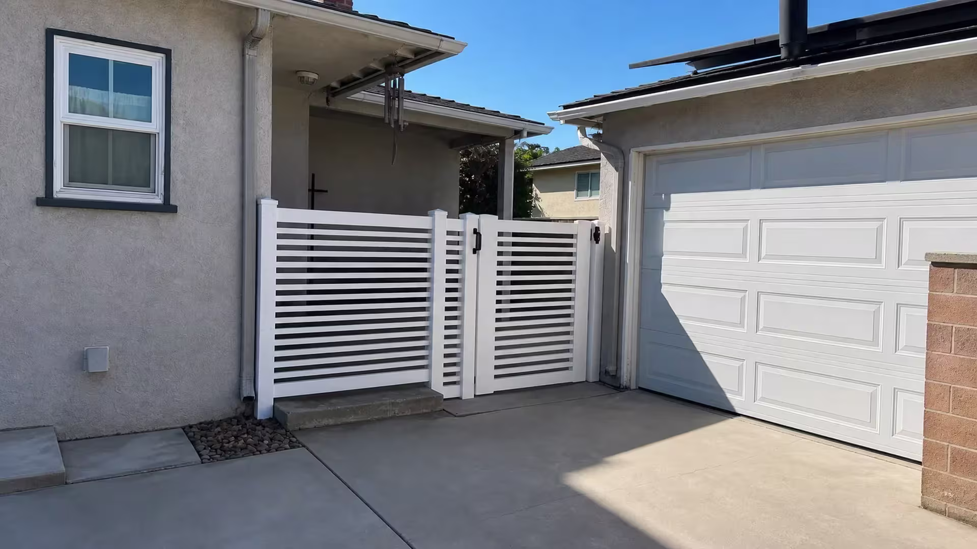 Solar panels and a paneled garage door rise behind this White horizontal picket vinyl fence in Arcadia