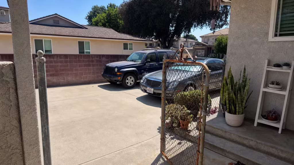 Before installation, a rusty chain-link gate stands beside porch steps and a concrete driveway.