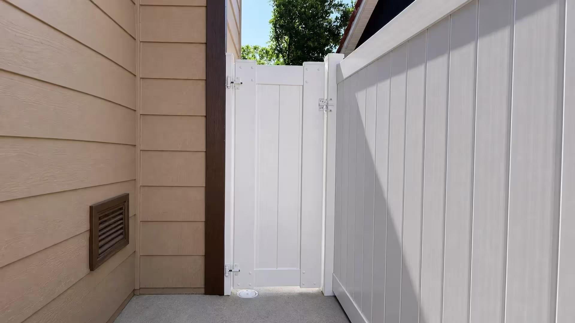 A matching White vinyl picket gate finishes the fence line across a narrow Chino side passage