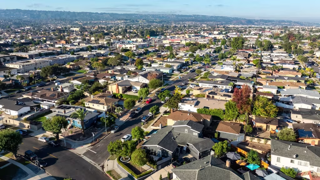 Harbor City's packed residential streets sit beneath a distant harbor skyline in this aerial frame