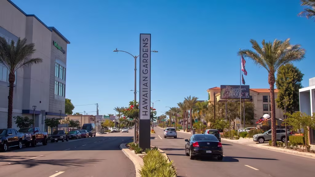 A commercial corridor runs past a city marker at street level here in Hawaiian Gardens