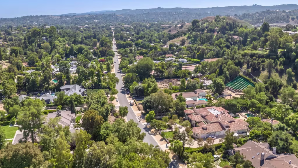 A wooded estate neighborhood spreads across a hillside in Hidden Hills, viewed from high aerial oblique