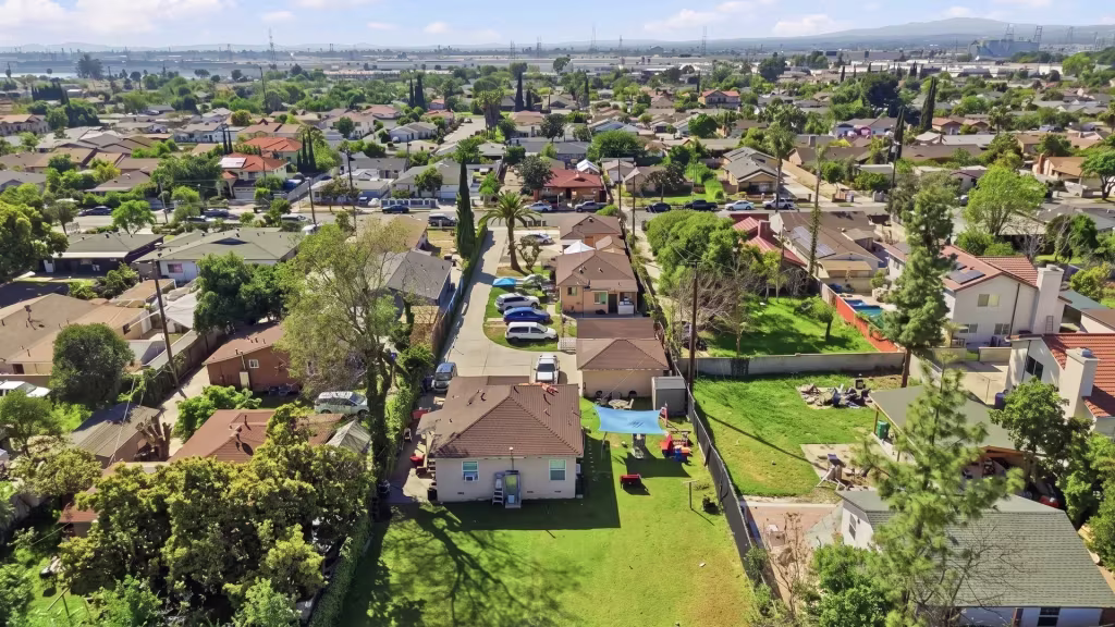 Suburban blocks and green yards spread across Irwindale, with an urban landscape rising in the distance