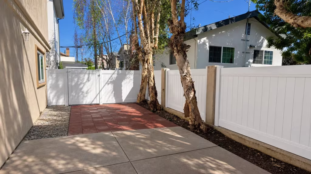 A red paver walkway leads to this White vinyl gate closing the privacy fence enclosure in Redondo Beach