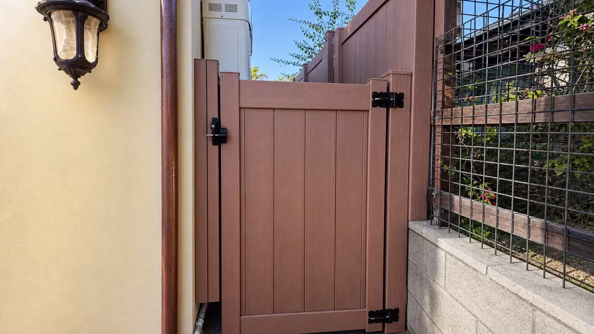 A flowering vine trellis stands beside the closed gate on this Siera Blend vinyl fence in Torrance