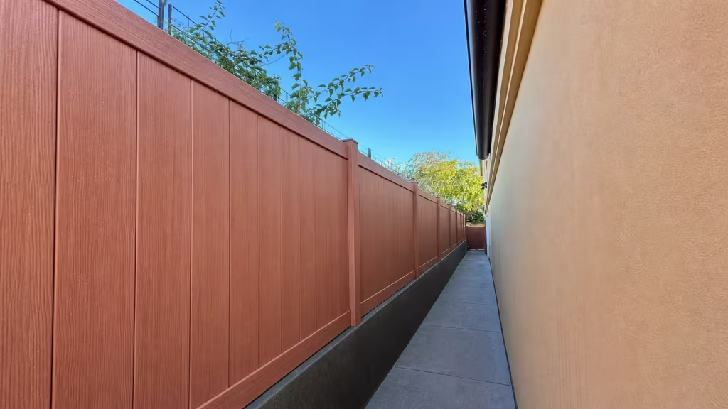 A masonry curb runs beside this Siera Blend vinyl privacy fence receding down a narrow Torrance passage