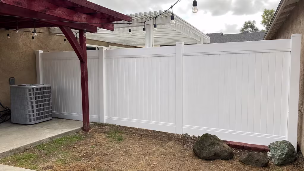 This vinyl fence, finished in White, ties into the existing concrete slab beneath a patio cover in La Verne