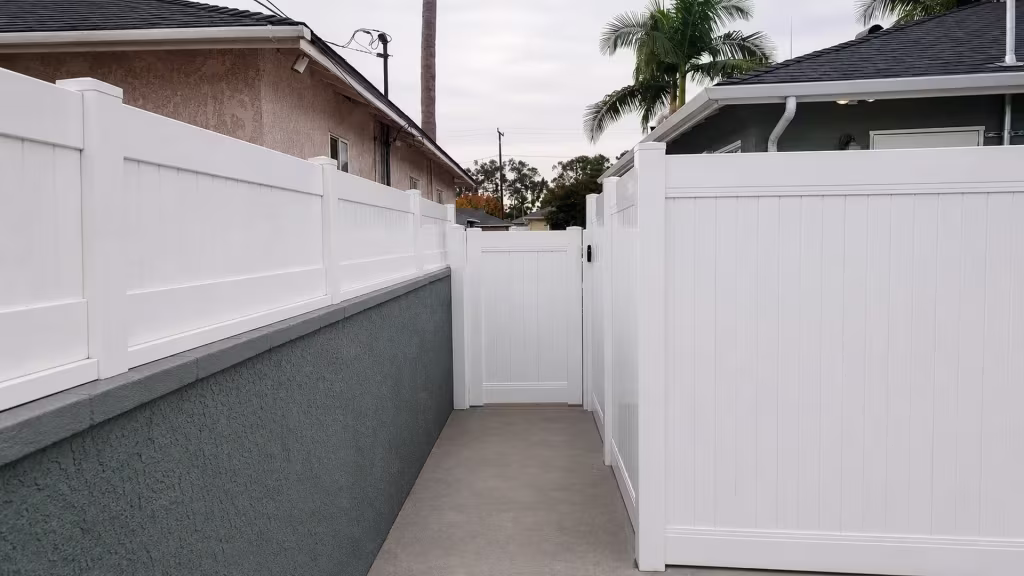 White vinyl fence panels frame a closed pedestrian gate crossing this Lakewood walkway