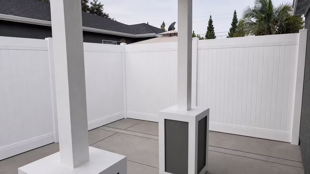 This White vinyl privacy fence turns an inside corner past a satellite dish and palm trees in Lakewood