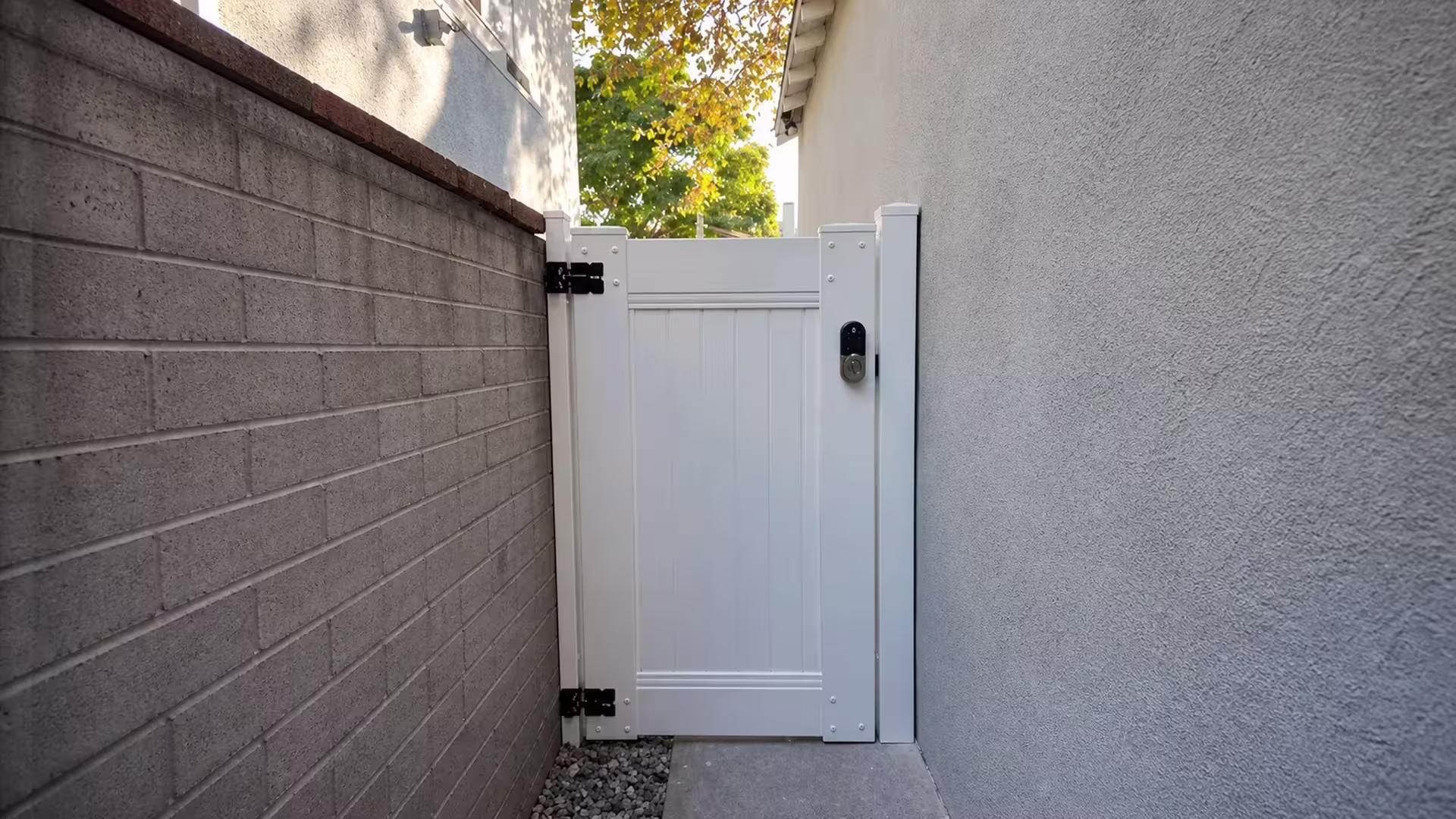 This White vinyl gate on the privacy fence sits between a block wall with a reddish brown cap and a stucco wall in Burbank