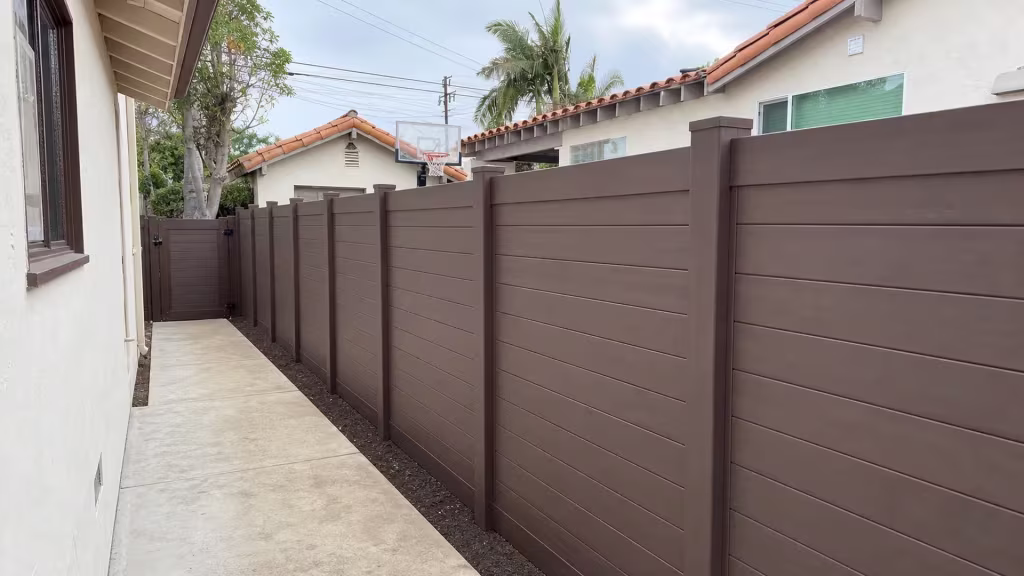Gabled stucco details and an exposed eave rise behind this Dark Sequoia vinyl fence in Los Angeles