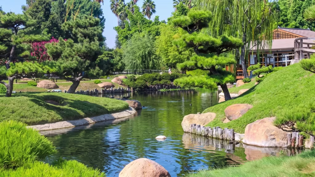 A landscaped lake in Lake Balboa park is bordered by trees and open lawn at ground level