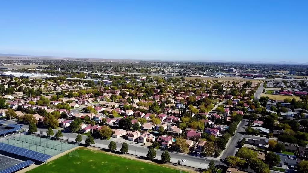 A wide desert-city grid forms Lancaster, with distant hills closing the horizon in this aerial view
