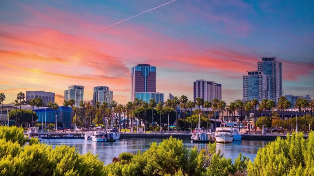 A marina waterfront and downtown skyline catch sunset light in this Long Beach panoramic view