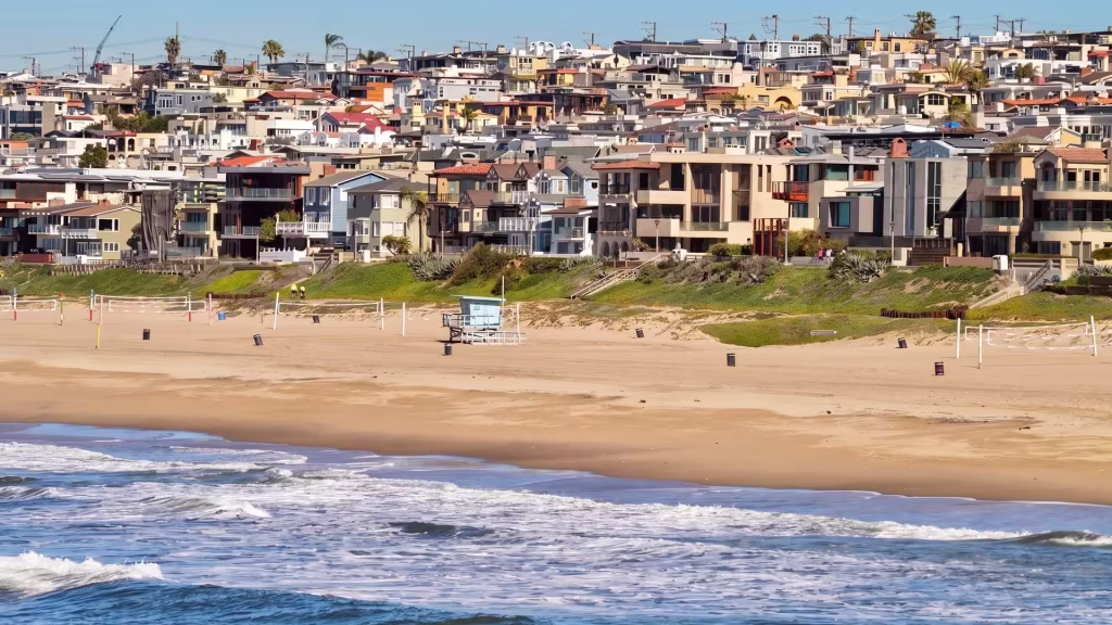 A panoramic beachfront in Manhattan Beach stretches between the open ocean and rows of coastal homes