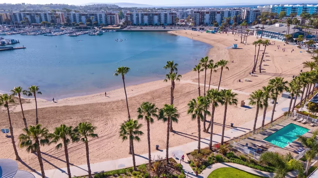 A marina basin, beach, and waterfront development fill this high aerial view over Marina Del Rey