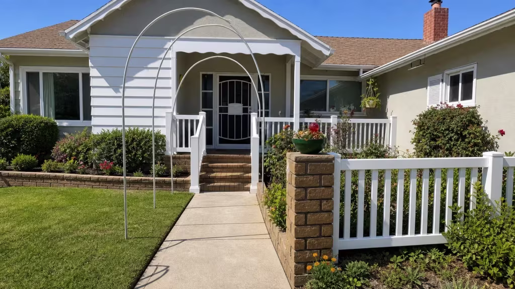 A red-brick chimney and planter rise beside this White vinyl picket fence, its railing meeting a Long Beach porch