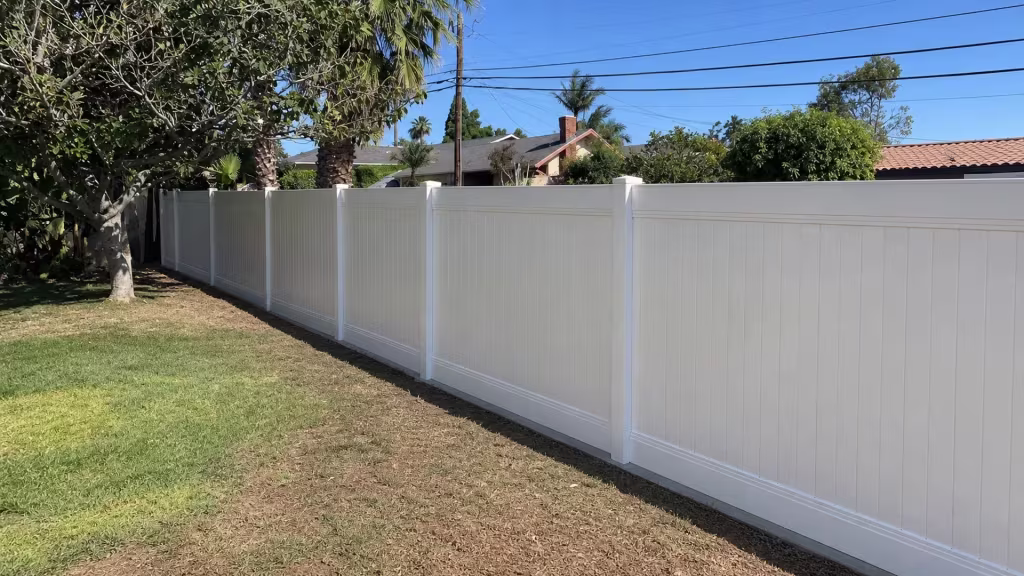 A red-orange roof edge shows above this vinyl fence, finished in White, along a Rancho Palos Verdes sidewalk