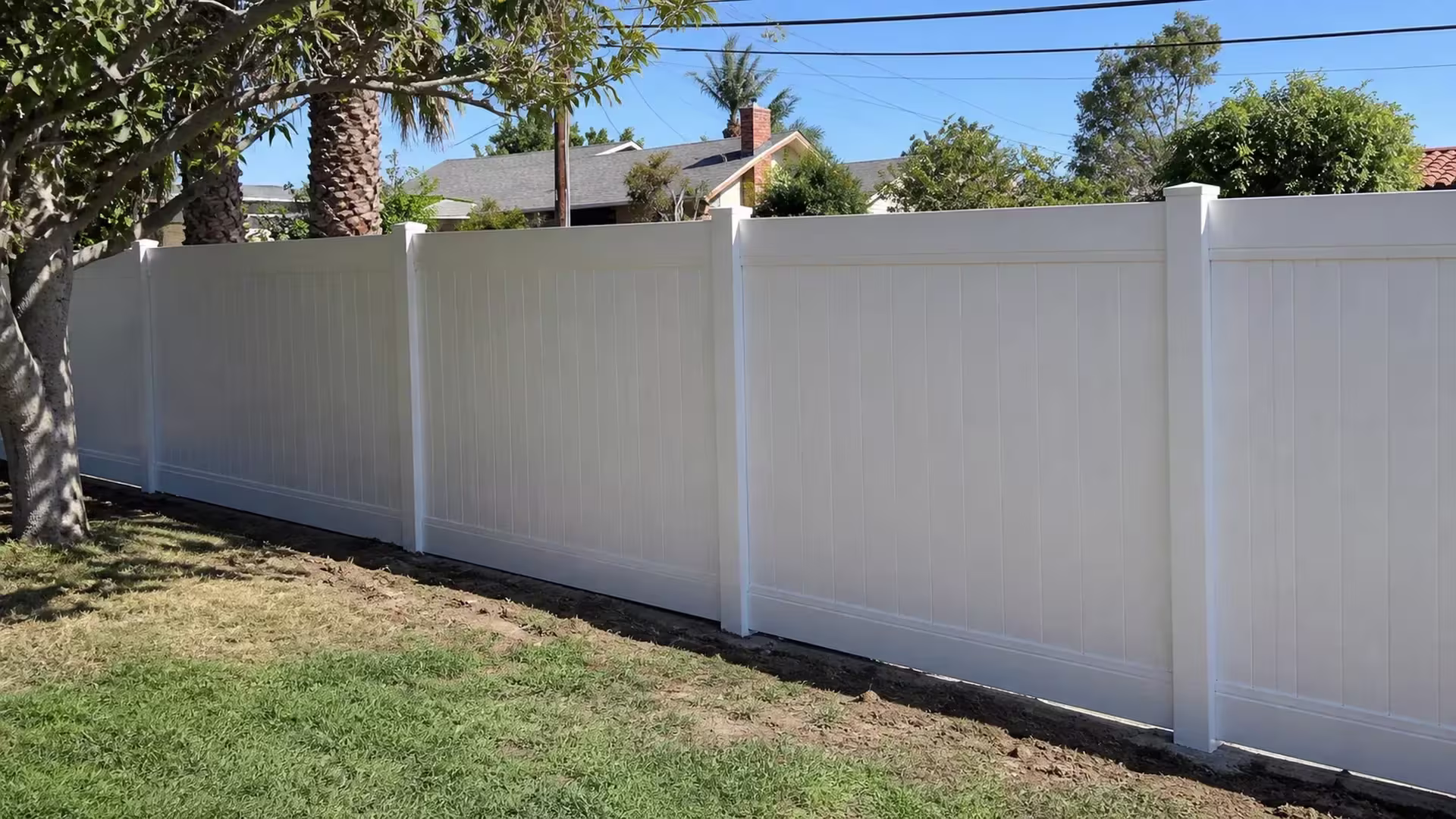 White vinyl privacy fence running along a bare earth strip in a Rancho Palos Verdes yard