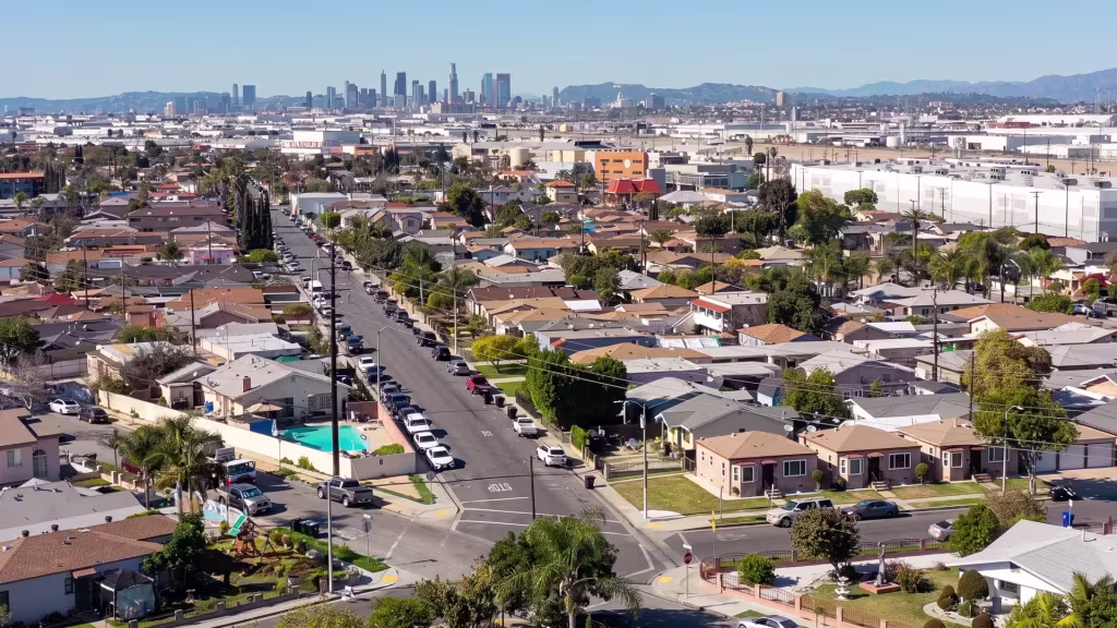A dense low-rise neighborhood fills Maywood, with a downtown skyline showing far in the distance