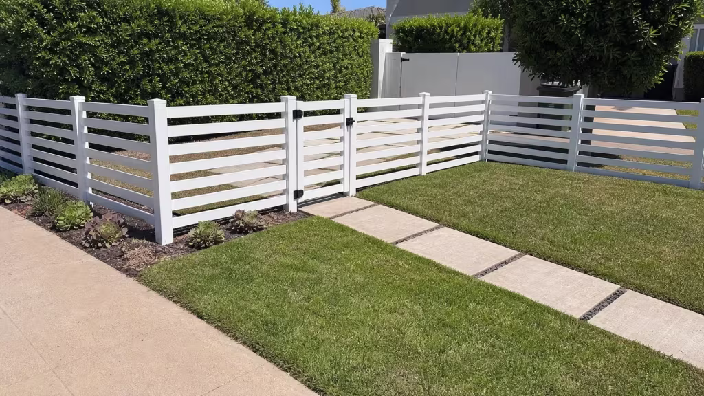 A corner return carries this White horizontal-picket vinyl fence along a Westchester side lawn, past the stepping-stone walk